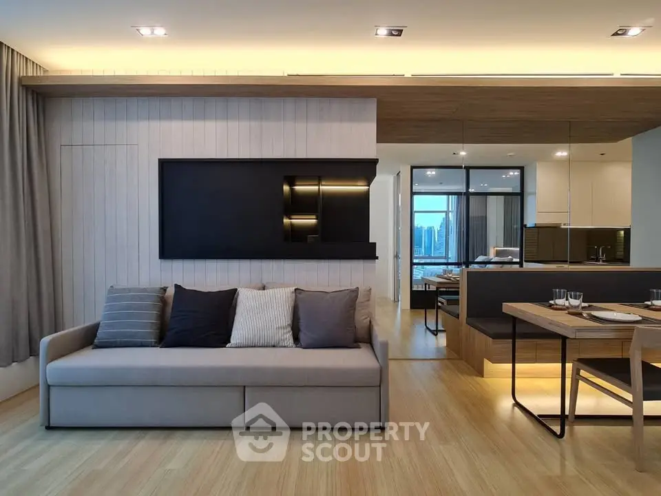 Modern living room with sleek design and open kitchen layout, featuring elegant lighting and stylish decor.