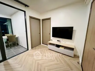 Modern living room with sleek TV setup and glass-enclosed balcony, perfect for urban living.