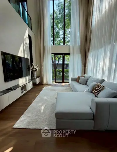 Luxurious living room with high ceilings, large windows, and elegant decor in a modern home.