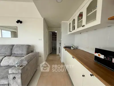 Modern living room with sleek kitchen and cozy sofa in open layout apartment.