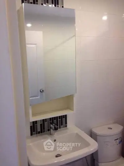 Modern bathroom with sleek sink and mirror cabinet, ideal for compact spaces.