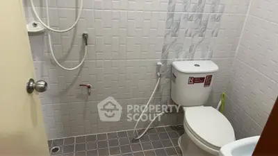 Compact bathroom with shower and toilet in modern tiled design.