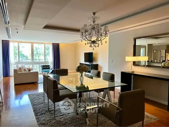 Luxurious dining area with elegant chandelier and glass table in spacious living room.