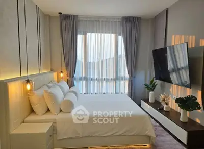 Modern bedroom with elegant decor, large window, and wall-mounted TV in a stylish apartment.