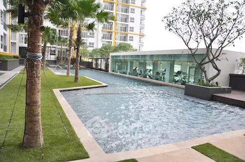 Luxurious apartment complex with stunning pool and lush greenery.