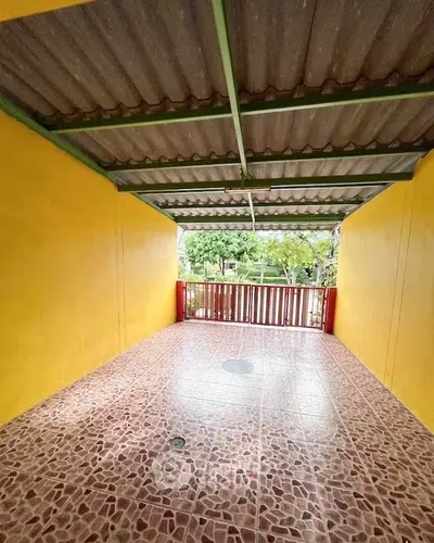 Spacious covered balcony with vibrant yellow walls and tiled flooring, perfect for relaxation.