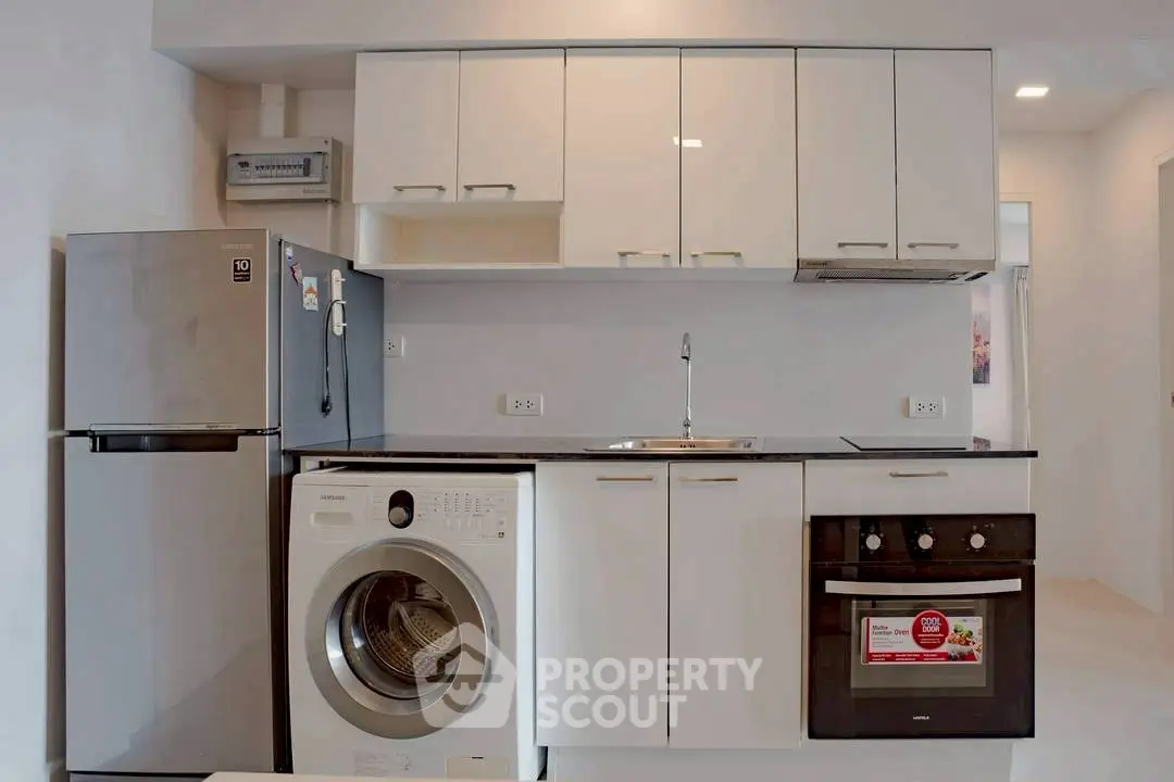 Modern kitchen with sleek appliances including washing machine and oven, perfect for urban living.