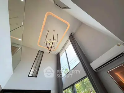 Modern high-ceiling living room with elegant lighting and large windows