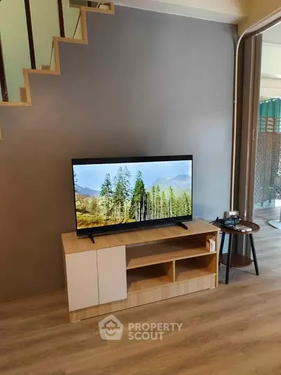 Modern living room with stylish TV stand and flat-screen TV under staircase