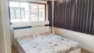 Cozy bedroom with large window and modern decor, perfect for relaxation.