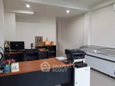 Modern office space with desk, computer, and printer in a well-lit room.