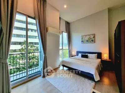 Spacious bedroom with large windows and balcony in modern apartment