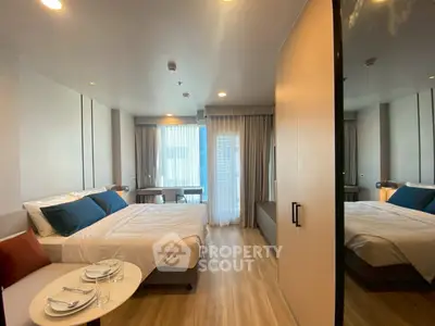 Modern bedroom with cozy bed, stylish decor, and natural light from large windows.