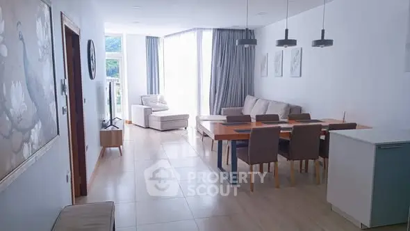 Spacious modern living room with dining area and large windows offering natural light.