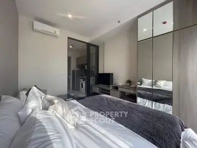 Modern bedroom with mirrored wardrobe and view into kitchen area