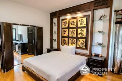 Elegant bedroom with polished hardwood floors and an exquisite traditional headboard, complemented by matching dark wood furniture.