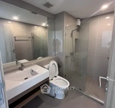Modern bathroom with sleek design, featuring glass shower and contemporary fixtures.