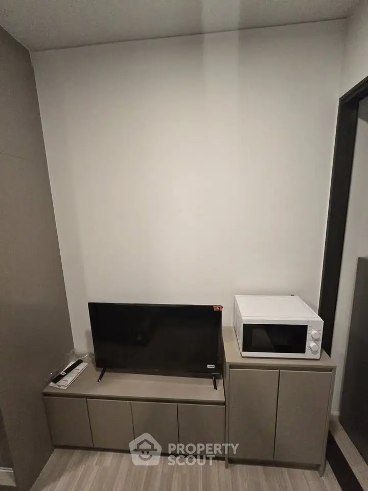 Modern living room with sleek TV stand and microwave, perfect for compact urban living.