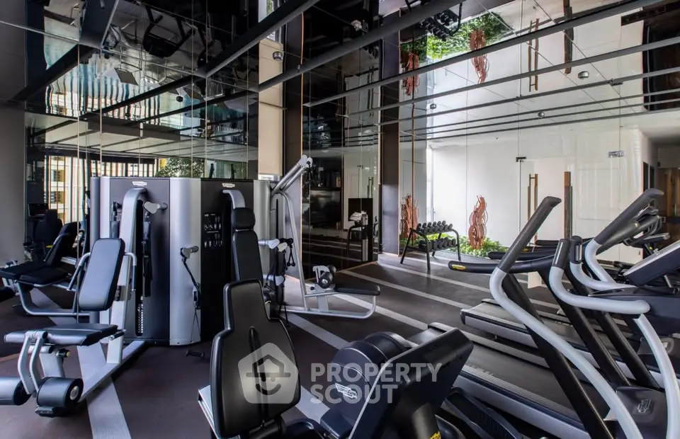 Luxurious modern gym with state-of-the-art equipment and mirrored ceiling in upscale residential building.