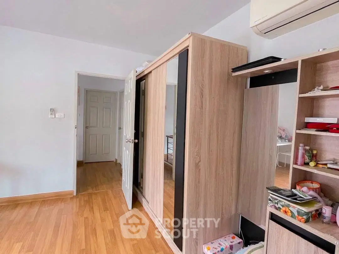 Spacious bedroom with wooden flooring and modern wardrobe in a cozy apartment.