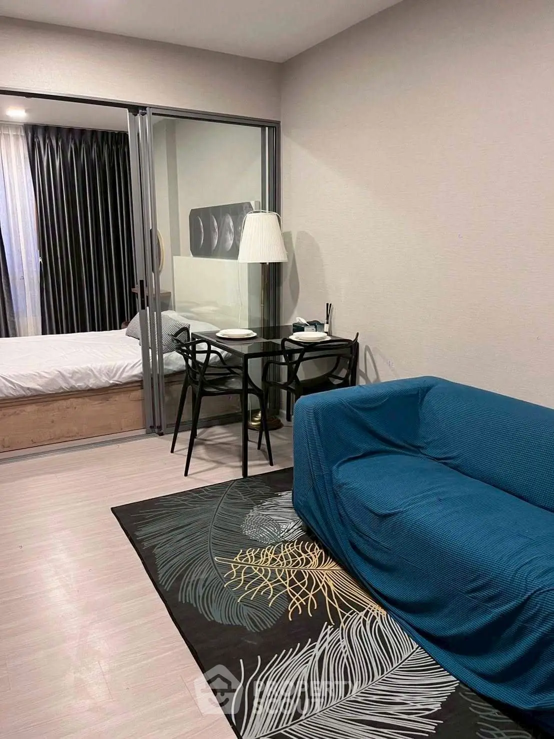Modern apartment interior with cozy living room and bedroom separated by glass doors, featuring stylish furniture.