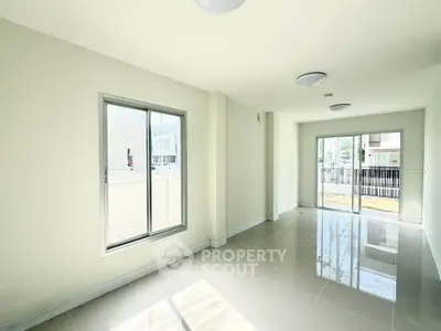 Spacious and bright living room with large windows and modern tile flooring.