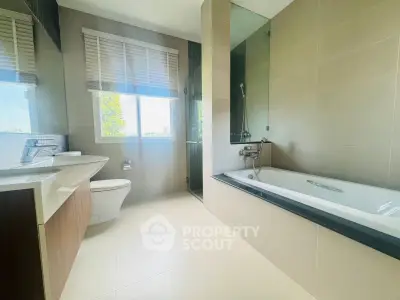 Spacious modern bathroom with bathtub and large window offering natural light.