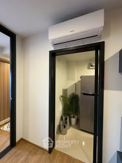 Modern interior with air conditioning and sleek refrigerator in a compact space.