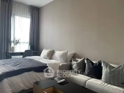 Modern bedroom with cozy bed, stylish sofa, and natural light from large window.