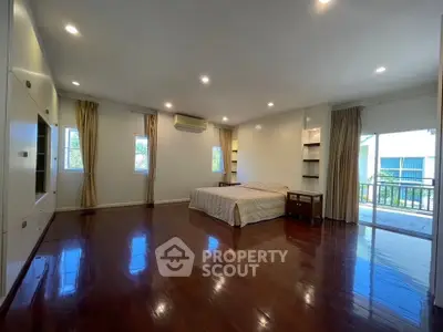 Spacious bedroom with polished wooden floors and balcony access
