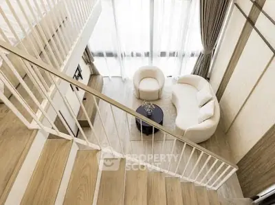 Elegant modern living room with high ceiling and stylish staircase, featuring cozy seating and large windows.