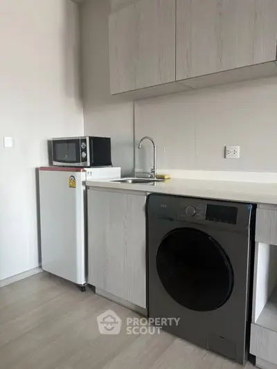 Modern kitchen with sleek appliances including a washing machine and microwave, perfect for urban living.