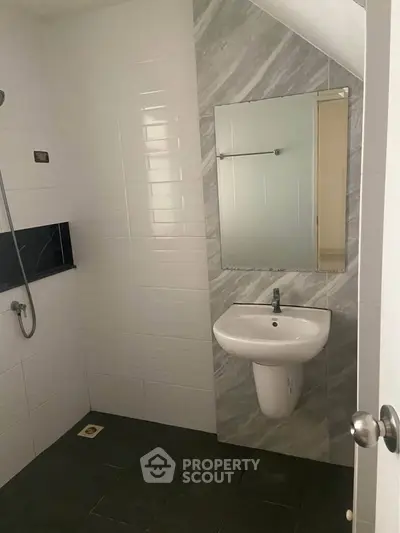 Modern minimalist bathroom with sleek white tiles and wall-mounted sink.