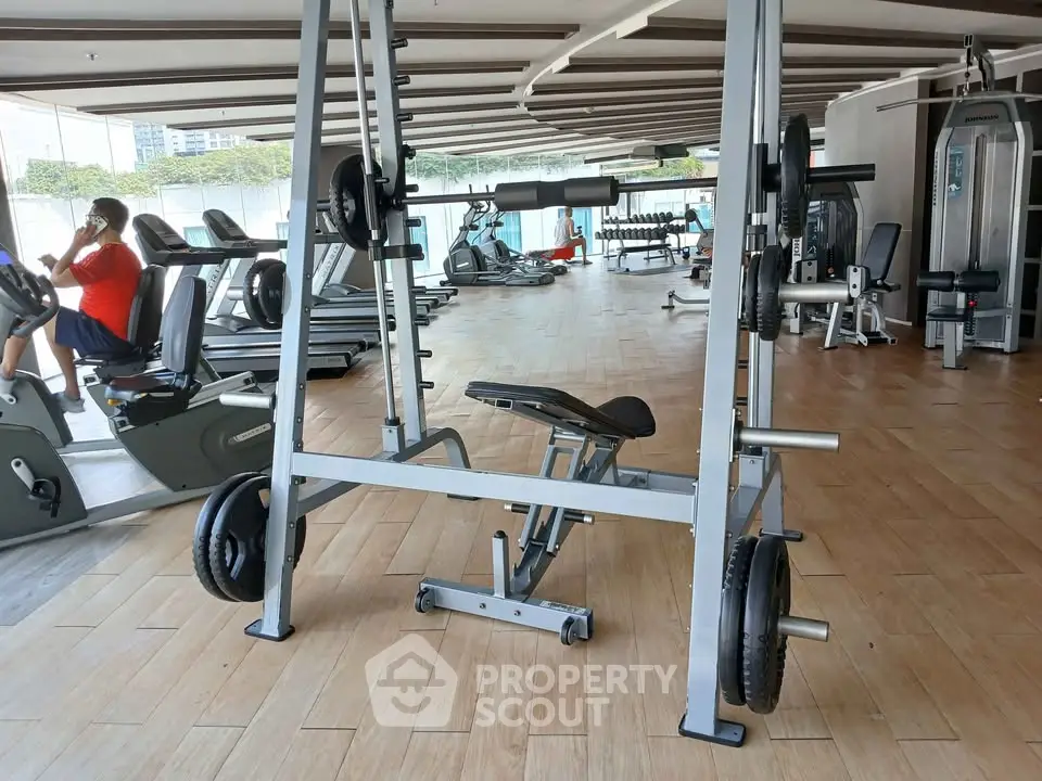 Spacious gym with modern equipment and wooden flooring in a luxury apartment complex.