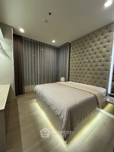 Luxurious modern bedroom with tufted wall and ambient lighting, perfect for relaxation and comfort.