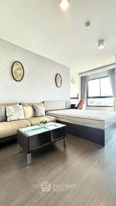 Modern studio apartment with stylish decor and large window offering natural light.
