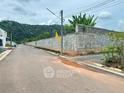 Scenic view of a quiet residential street with lush greenery and mountain backdrop.