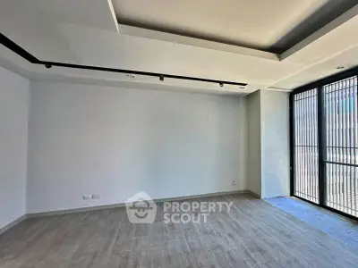 Spacious empty room with large windows and modern ceiling design, perfect for customization.