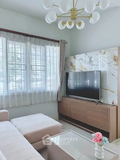Elegant living room with modern decor, featuring a stylish chandelier, marble accent wall, and cozy seating area.
