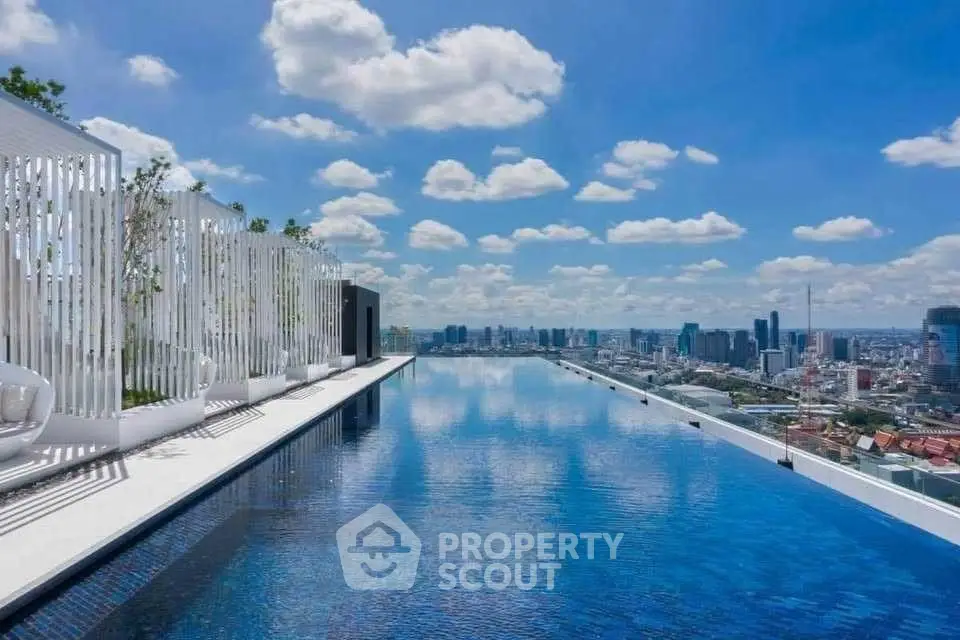 Stunning rooftop infinity pool with breathtaking city skyline view under a clear blue sky.