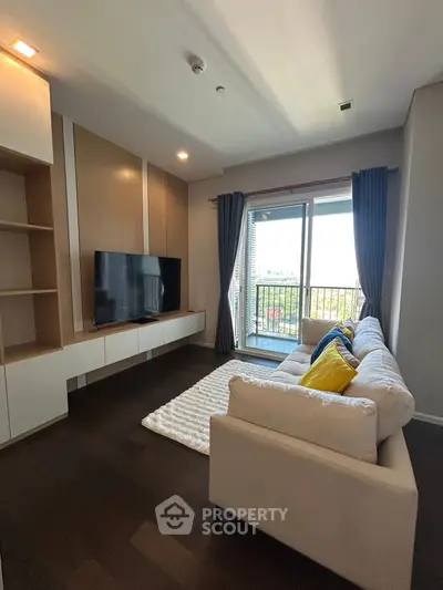 Modern living room with cozy sofa and large TV, featuring a balcony view.