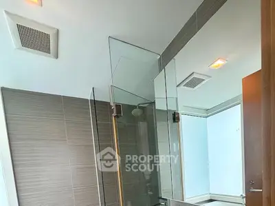 Modern bathroom with glass shower enclosure and sleek tile design.