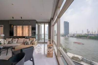Luxurious living room with stunning river view and modern decor in high-rise apartment.