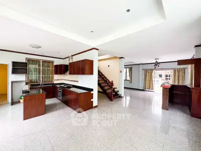 Spacious open-plan kitchen and living area with modern wooden cabinetry and large windows.