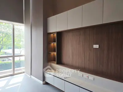 Modern living room with built-in shelving and large windows offering natural light