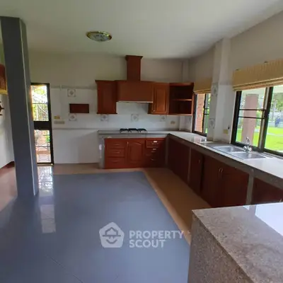 Spacious kitchen with modern cabinetry and dual sinks, overlooking a lush garden view.