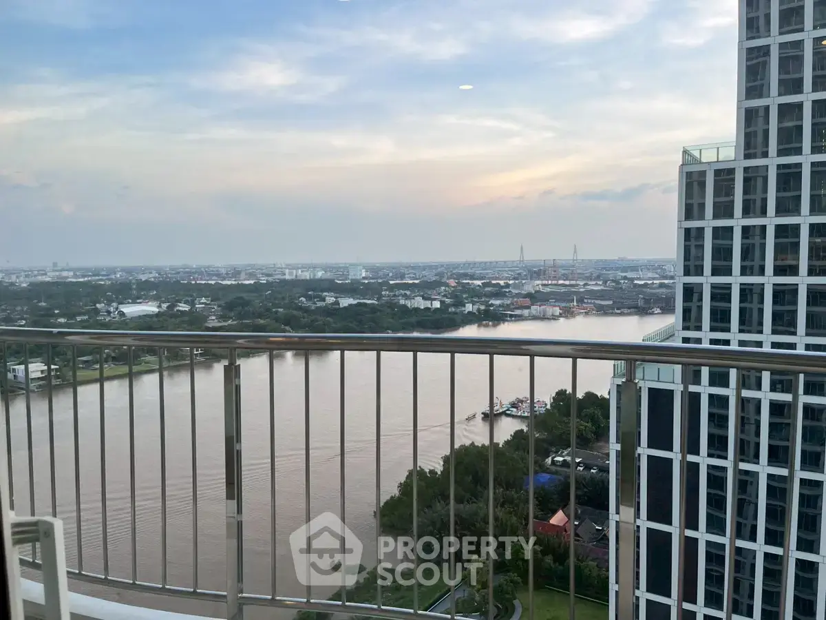 Stunning high-rise balcony view overlooking a serene river and cityscape, perfect for urban living.