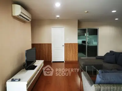 Spacious living room with modern furniture and air conditioning, featuring a sleek TV setup and wooden flooring.