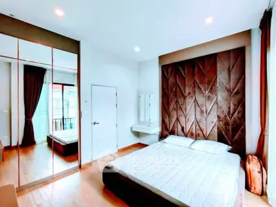Luxurious bedroom with plush headboard and mirrored wardrobe in modern apartment