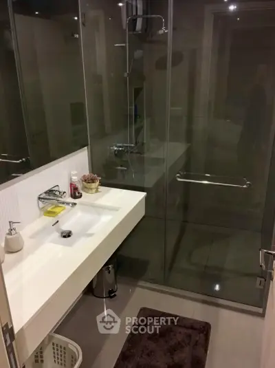 Modern bathroom with sleek glass shower and stylish sink in contemporary home.